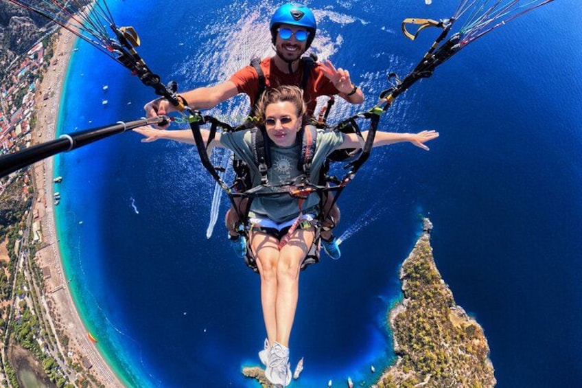 Une personne pratiquant le parapente au-dessus d’une zone côtière, avec une vue dégagée sur la plage et une île au loin. 2