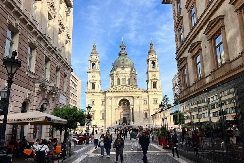 A historic building with two towers and a dome, surrounded by cafes and pedestrians. 3