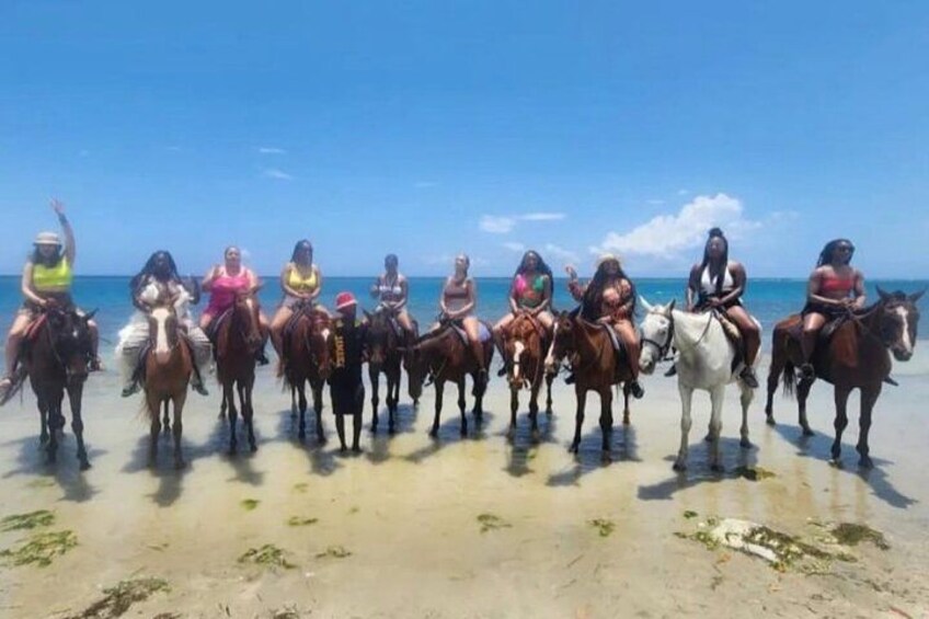Een groep mensen die paardrijdt op het strand. 4