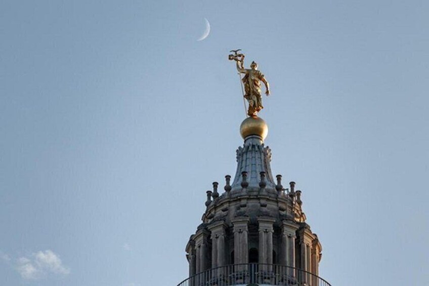 A building with a golden statue on top, a clear sky, and a crescent moon. 4