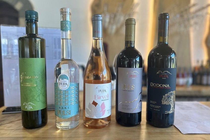 Fyra flaskor Pupa-vin på en träyta. 1