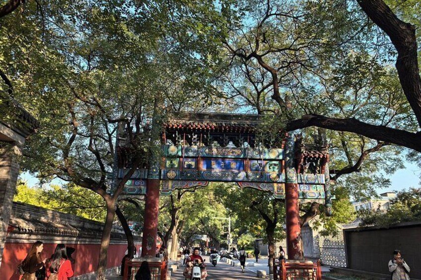 A traditional Chinese pavilion with intricate designs, surrounded by trees and a busy street. 3