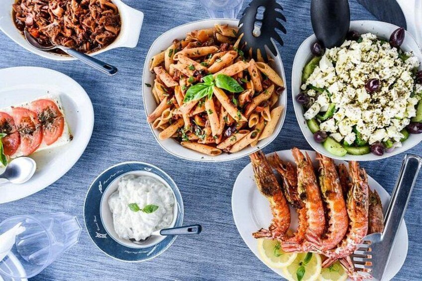 A variety of Mediterranean dishes including grilled shrimp, pasta, and a salad with feta cheese. 3