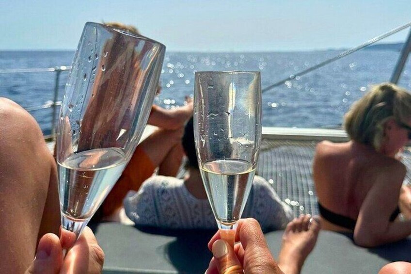 Two people holding champagne glasses with a body of water and a boat in the background. 3