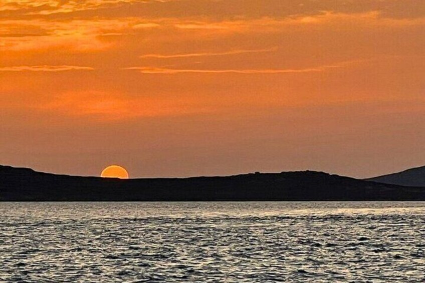 A sunset over a body of water with a silhouette of hills in the background. 2