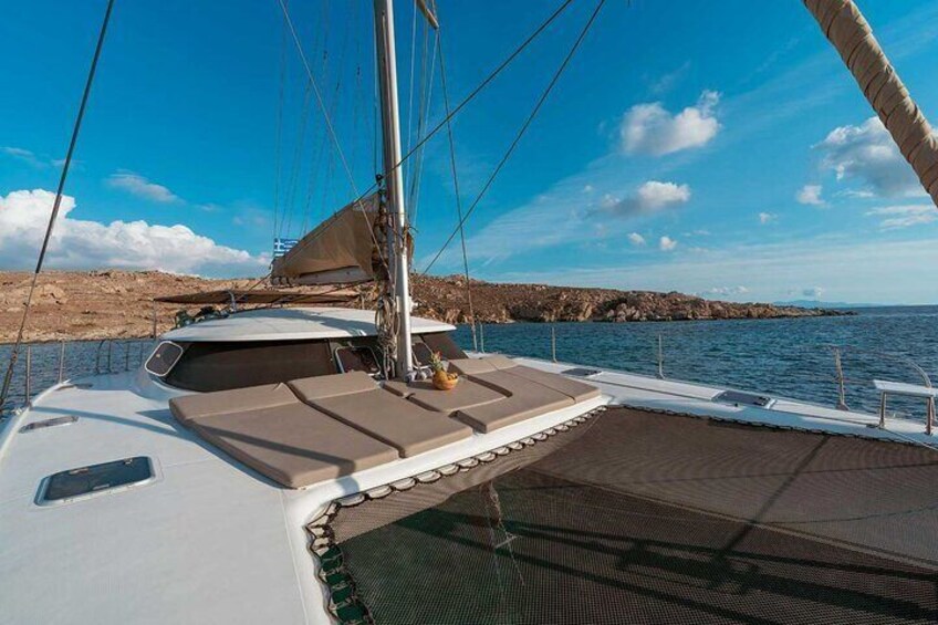 Un velero con cubierta protegida y una costa rocosa al fondo. 1