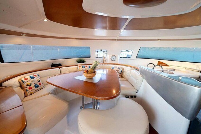 Interior de un yate con una mesa de comedor redonda, asientos acolchados y un panel de control. 5