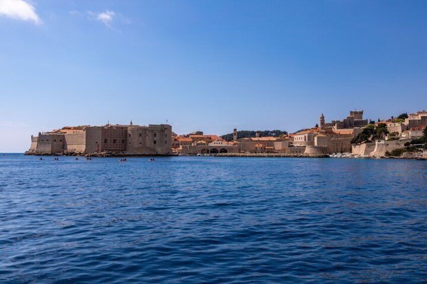 Un paysage urbain côtier, avec des bâtiments historiques et une imposante forteresse au bord de la mer. 2