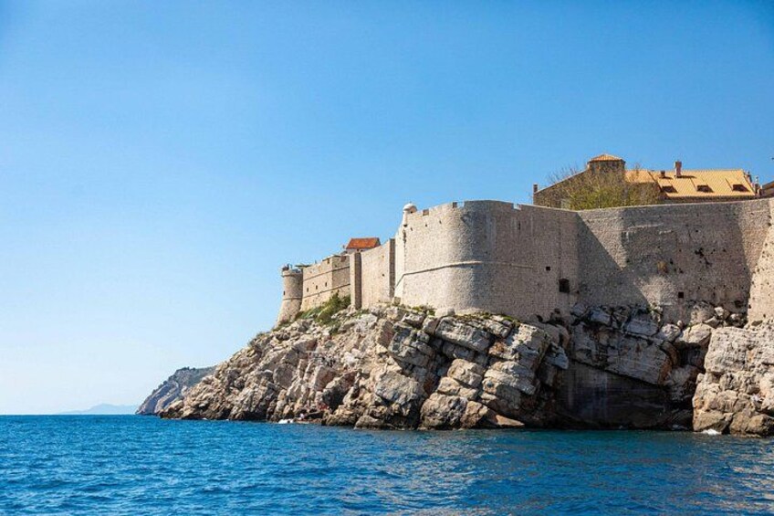 A historic stone fortress on a rocky coastline with clear blue waters. 3