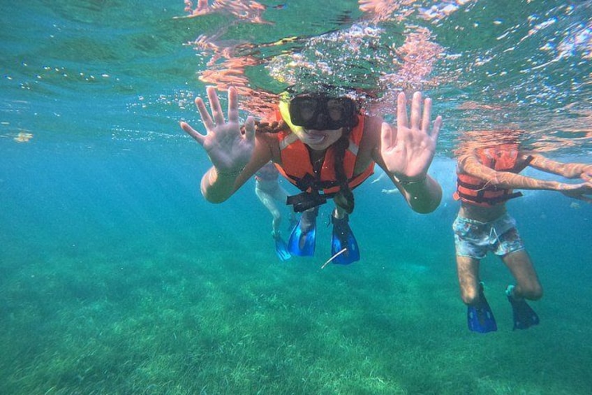 Two people underwater, one wearing a snorkel and fins, and the other in a life jacket. 2