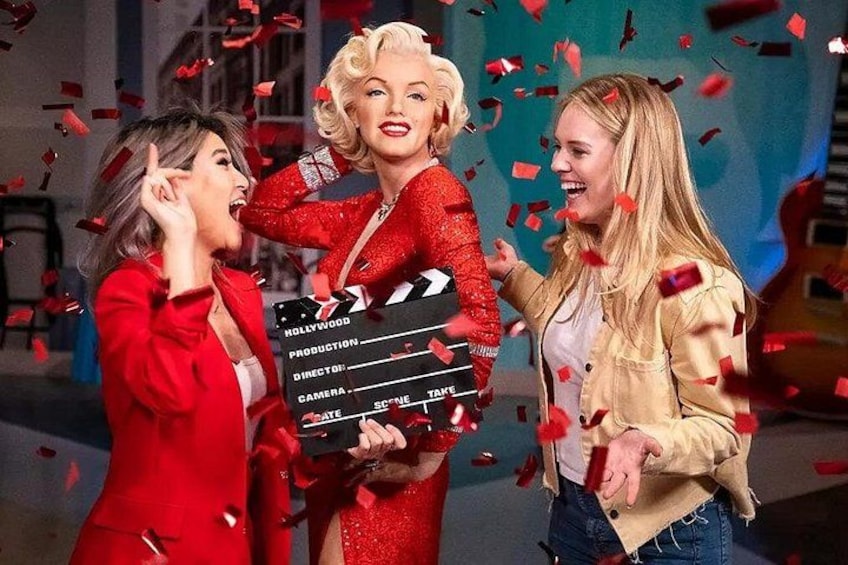 A clapperboard, a person in a red dress, and confetti. 1