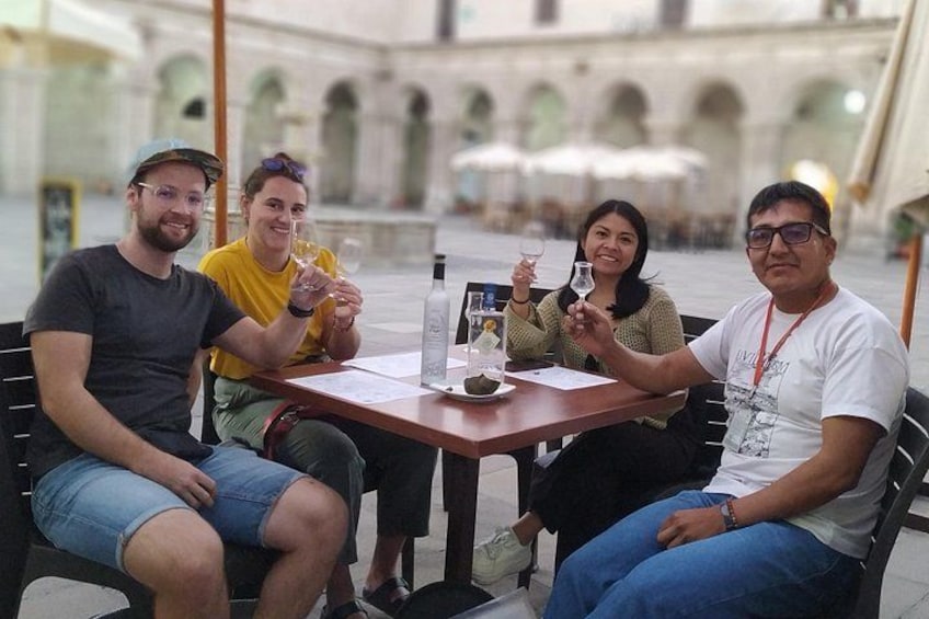 Cuatro personas sentadas en una mesa en un entorno al aire libre con arcos al fondo. 1