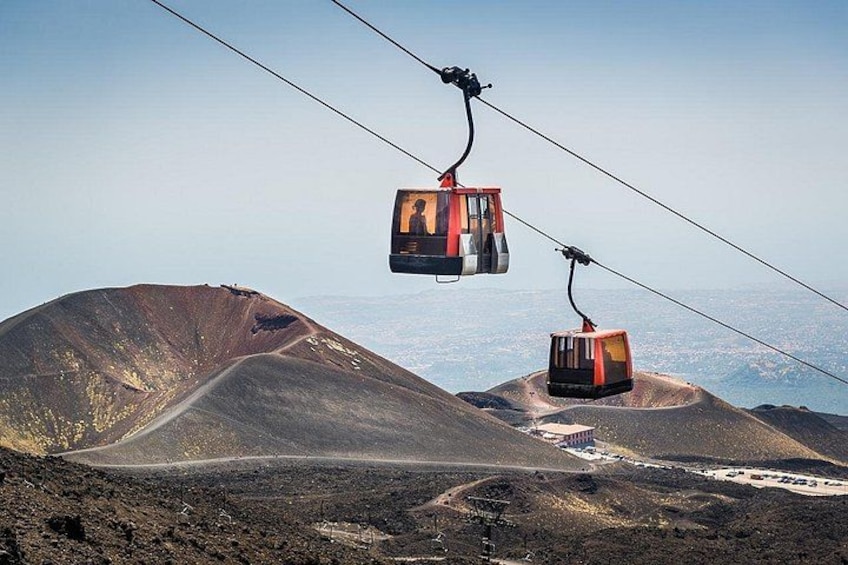 A cable car system in a volcanic landscape with a clear sky. 3