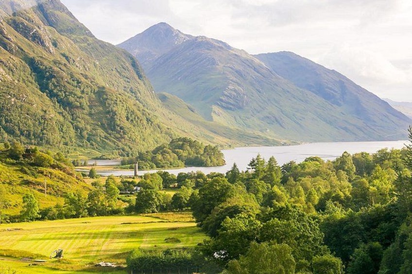 A mountainous landscape with a lake, green fields, and a building. 2