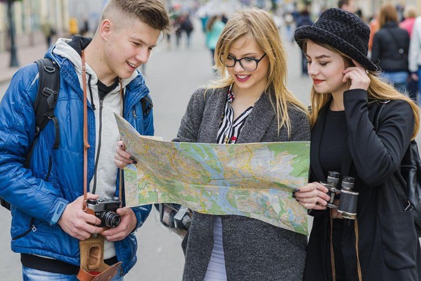 Trois personnes sont penchées sur une carte, l’une d’elles tient un appareil photo, et une autre a des jumelles. 3