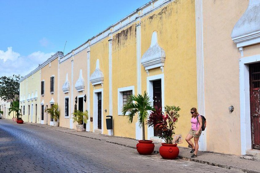 A yellow building with white trim and red planters on a cobblestone street. 3
