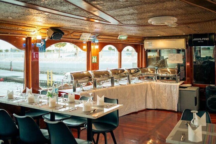 A dining area with tables set for service, a buffet line, and a view of the water outside. 3