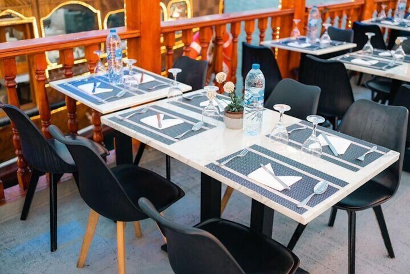 Outdoor dining tables with black chairs, water bottles, and potted plants. 2