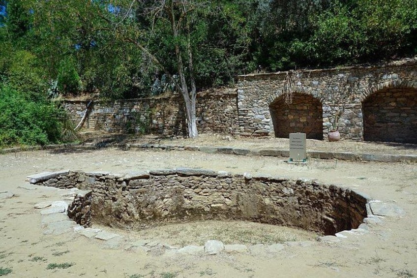 Un site archéologique comprenant une vaste zone de fouilles, des murs en pierre et un panneau d’information. 5