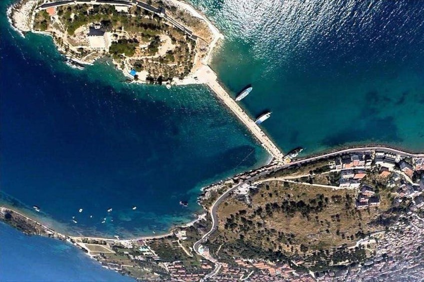 Vue aérienne d’une zone côtière avec une petite île, une jetée et une péninsule densément urbanisée. 4