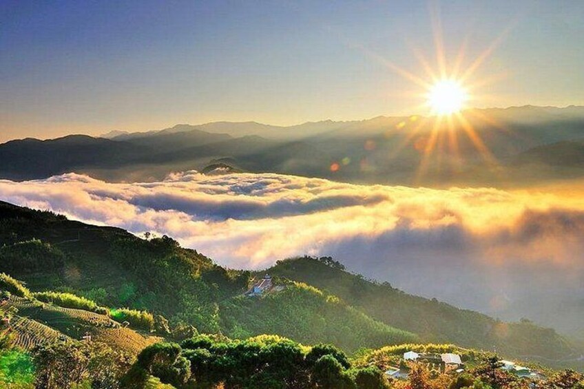 A sunrise over a mountainous landscape with terraced fields and a village below. 3