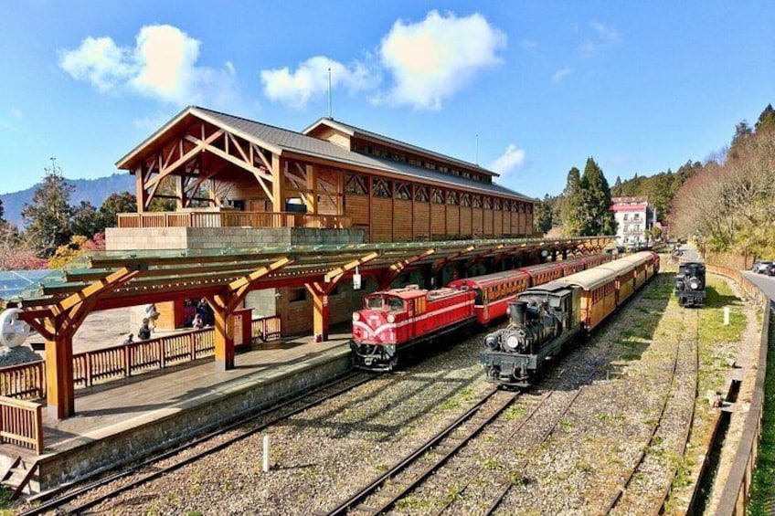 A wooden train station with multiple tracks and trains, surrounded by a scenic landscape. 2