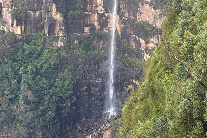 A waterfall cascading down a rocky cliff surrounded by dense green forest. 5