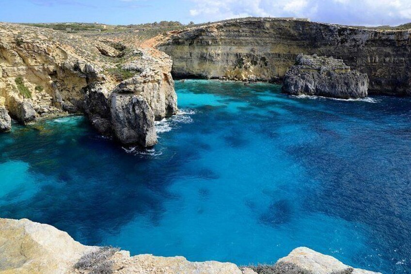 A coastal landscape with rocky cliffs and clear blue waters. 2
