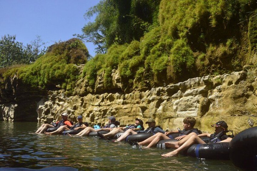 People floating on water in tubes near a rocky cliff. 5