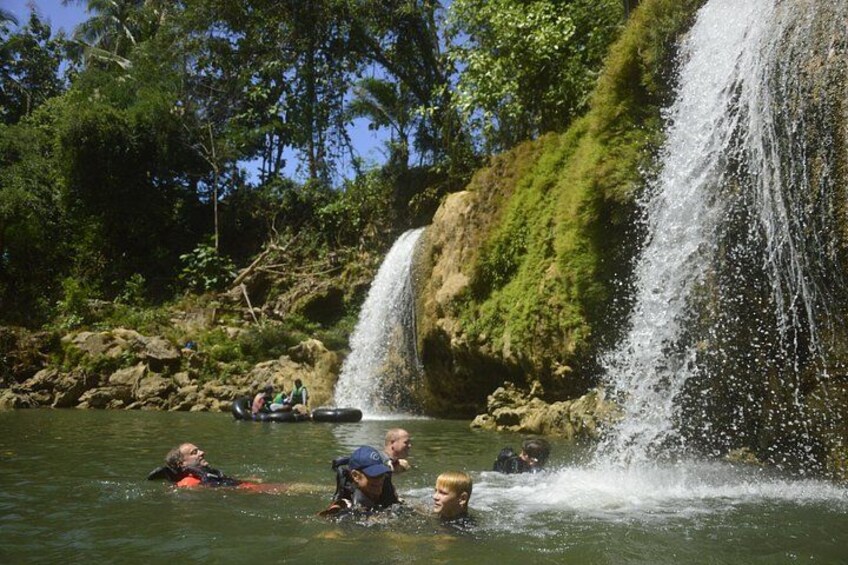 A waterfall, people swimming, and lush greenery. 3