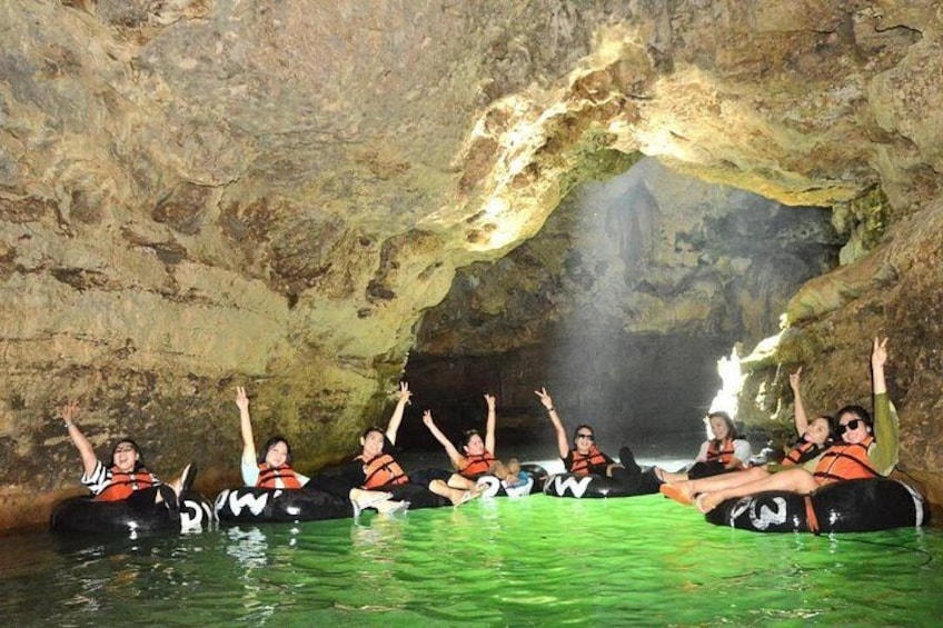 People in a cave with a large archway, sitting on inflatable tubes. 1