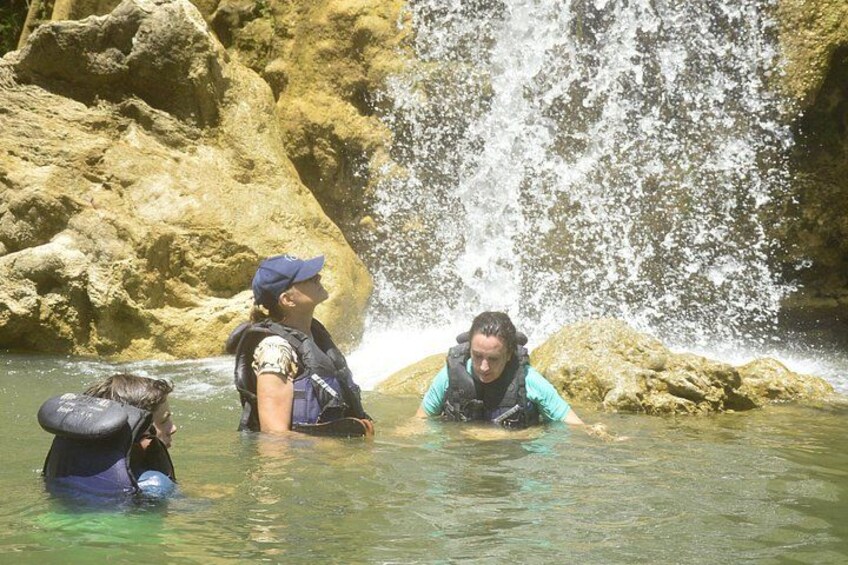 People in water near a waterfall. 4