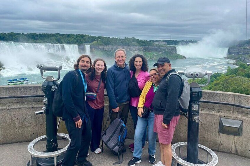 A group of people standing on a viewing platform with a waterfall in the background. 1