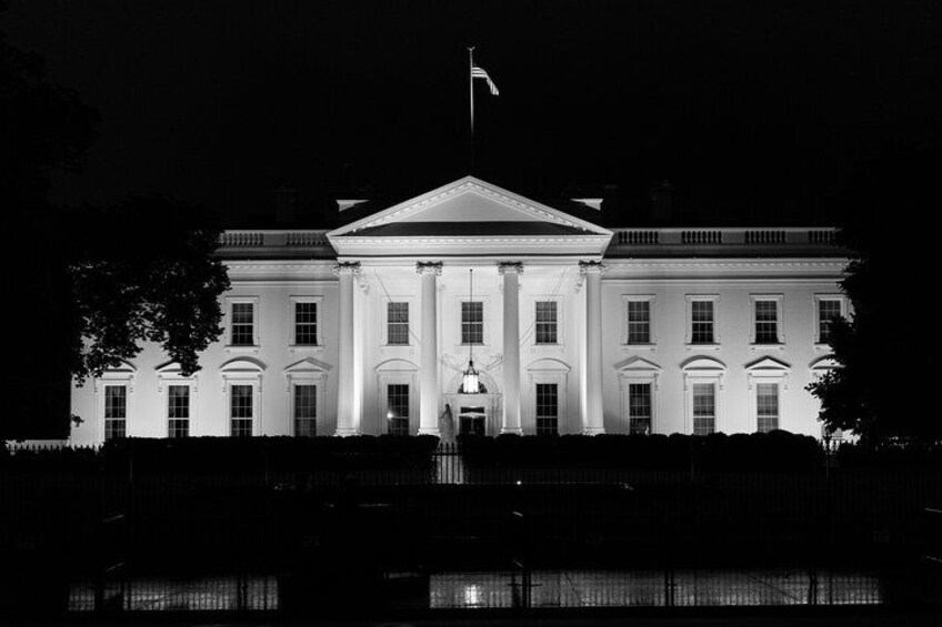 A large, illuminated building with a central entrance and columns, surrounded by a reflective water body. 2