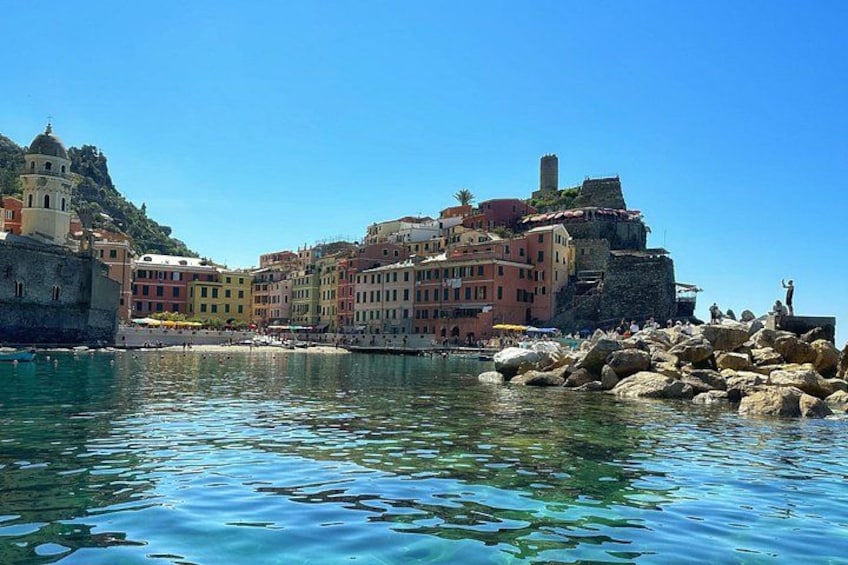 A coastal town with colorful buildings, a clear blue sea, and rocky outcrops. 2