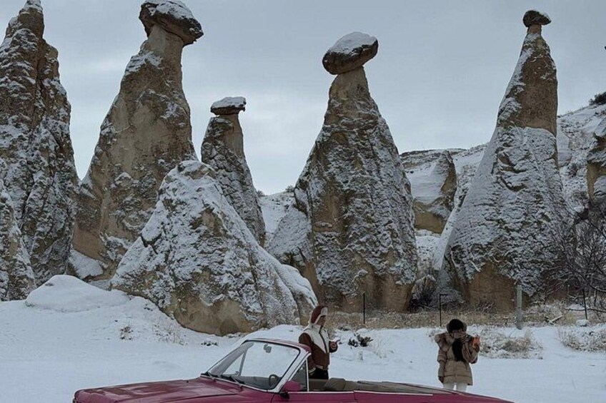 A snowy landscape with unique rock formations and a red car. 5