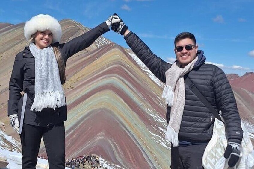 Two people standing in front of a colorful mountain range. 3