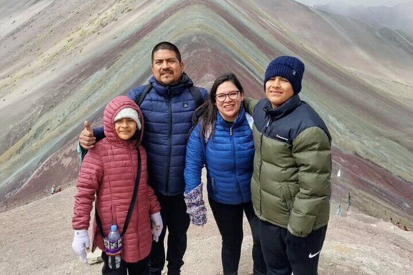 A family of four standing in front of a colorful geological formation. 2