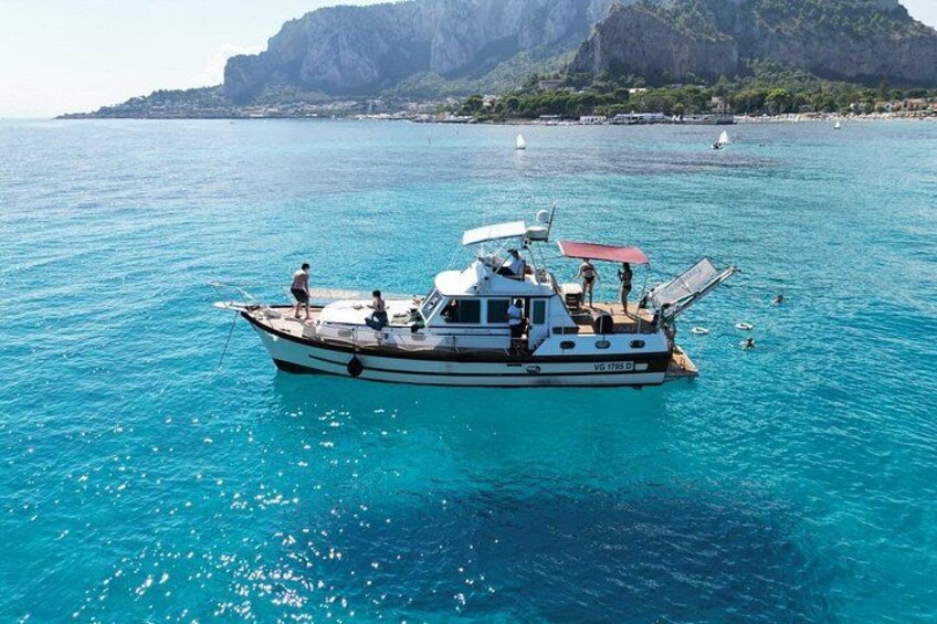 A boat on turquoise water with a mountainous landscape in the background. 3