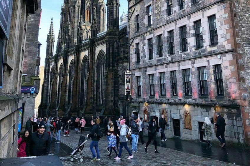 Een drukke straat met historische gebouwen, waaronder een kathedraal met hoge torens. 4