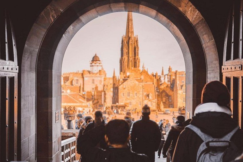 Een groep mensen kijkt door een poortbogen naar een stadsgezicht met een opvallende kerktoren. 3