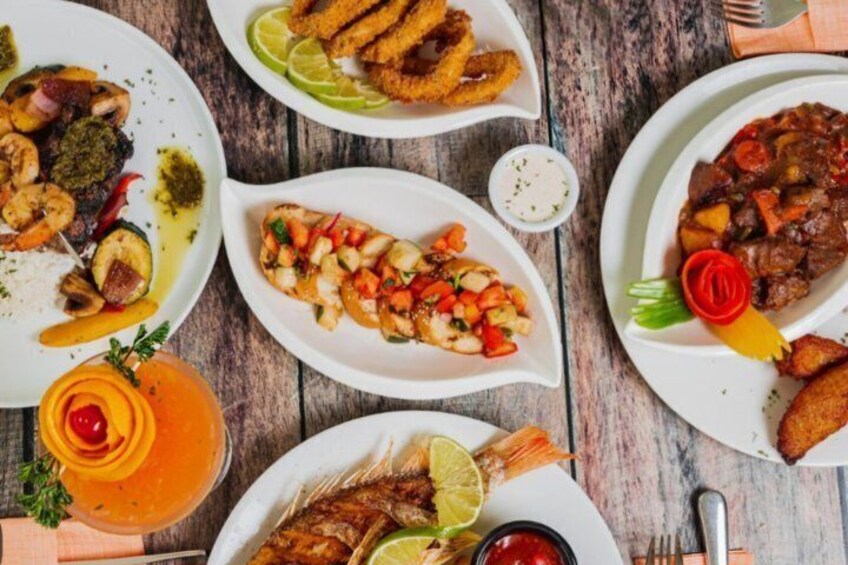 A variety of seafood dishes on plates, a drink with a garnish, and a rustic wooden table. 4