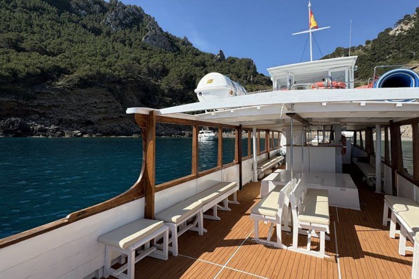 Ein Bootsdeck mit weißen Bänken und Tischen, einem Rettungsring und einer Flagge. 4