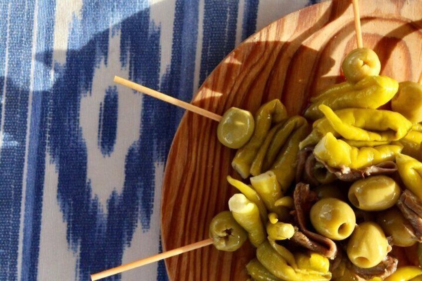 Une assiette en bois garnie de légumes marinés et d’olives. 3
