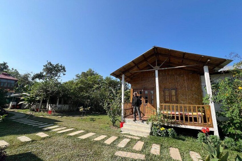 A wooden house with a porch, surrounded by a well-maintained lawn and garden. 5