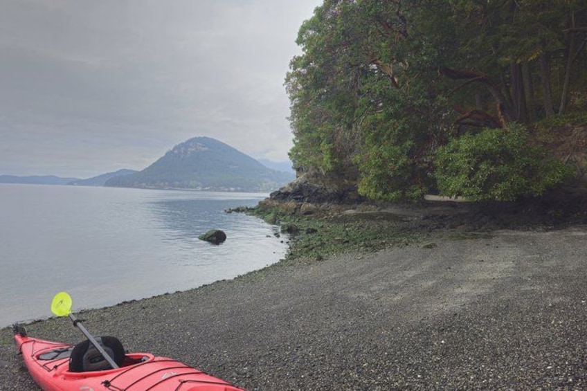 Un kayak sobre una orilla pedregosa con una montaña al fondo. 1