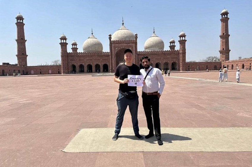 Two men standing in front of a large mosque with domes and minarets. 2