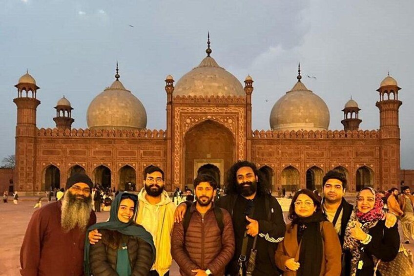 A group of people standing in front of a large, historic building with domes and minarets. 3
