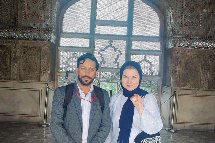 Two people standing in a room with ornate architecture and a large window. 4