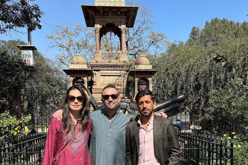 Three people standing in front of a historical monument with a large cannon. 1